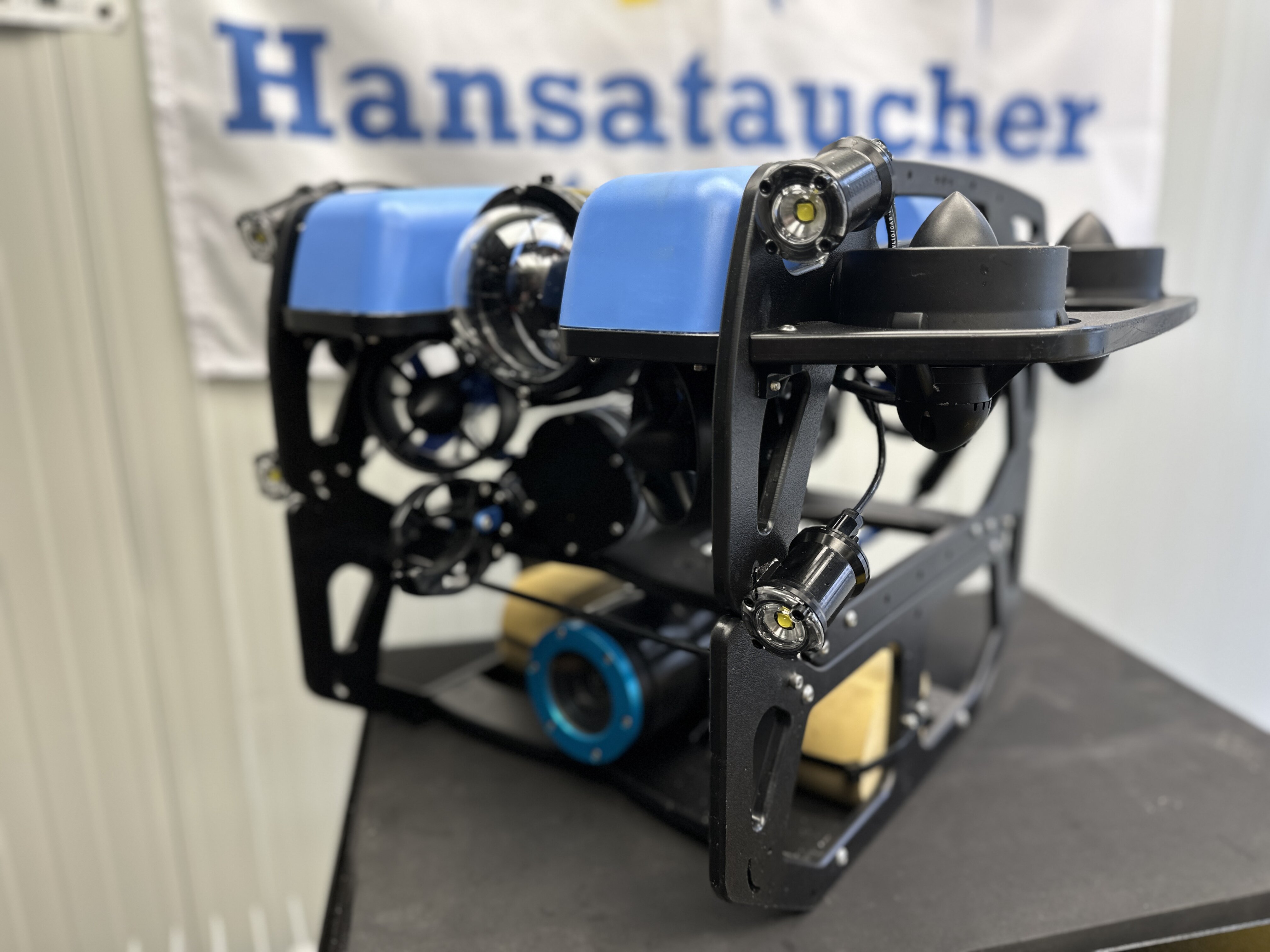 Tauchroboter mit schwarzem Metall und blauer Abdeckung auf einem Tisch.